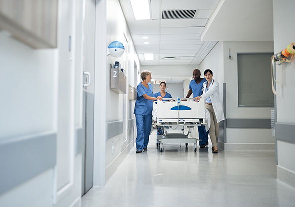 A group of doctors and nurses walking a patient on a hospital bed down a hospital hallway