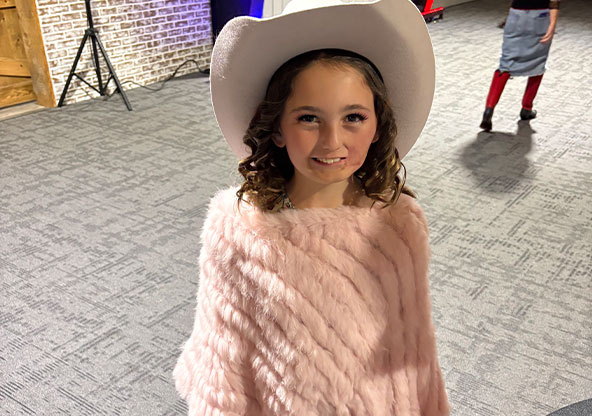 young girl with cowgirl hat and pink sweater