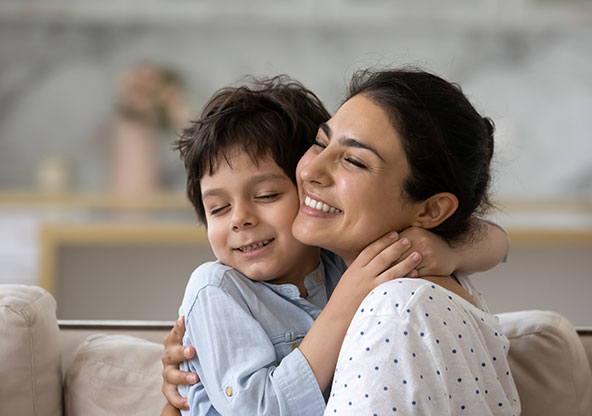 Young boy hugging mom and smiling