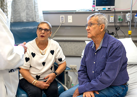 Pam and Kenneth Carrier sitting together in a hospital room, supporting each other during recovery from heart care.